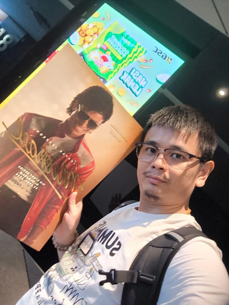 Selfie holding a large signed poster near GSC signage
