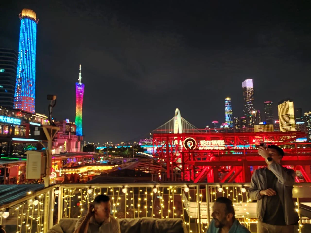 Night city skyline viewed from a rooftop gathering space