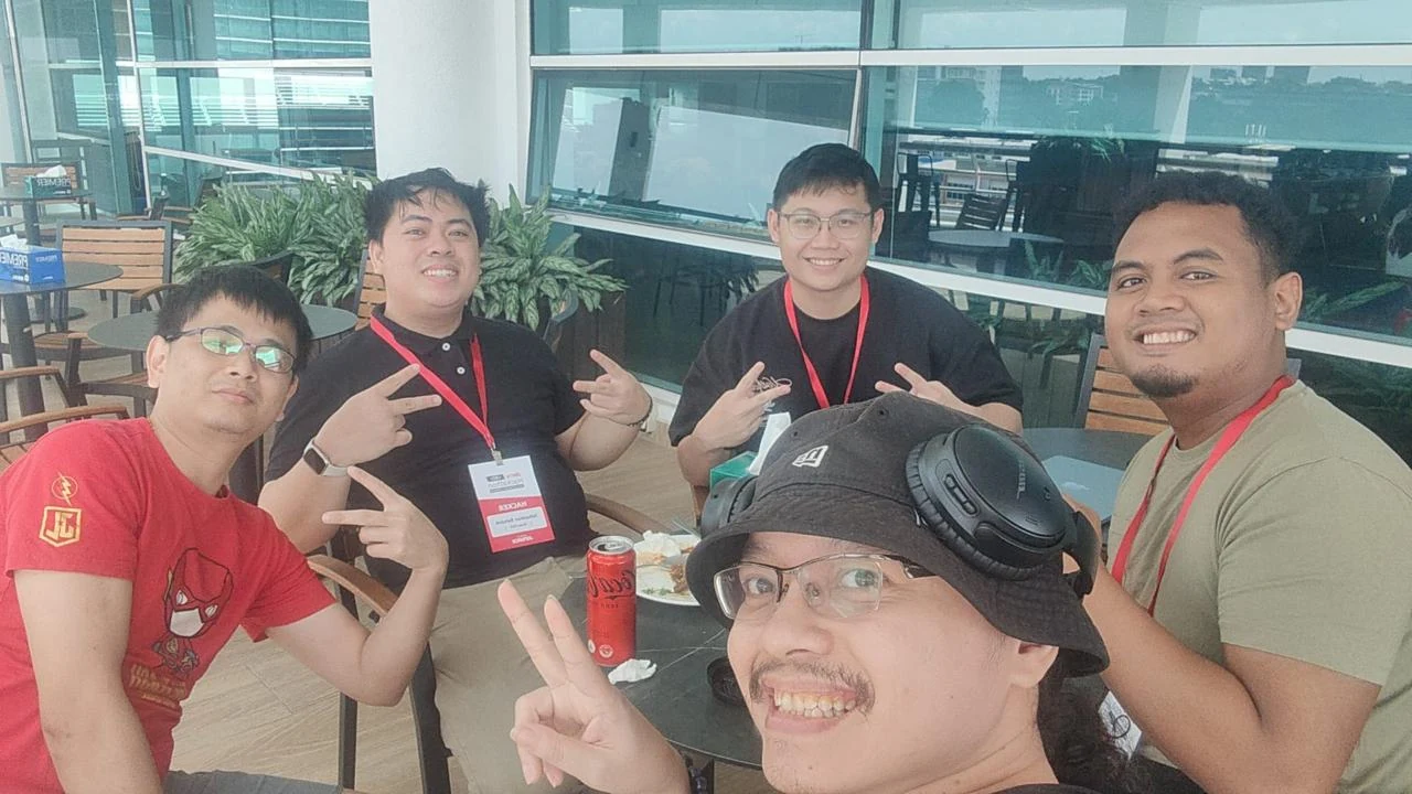 Five teammates taking a lunch selfie at a cafe table