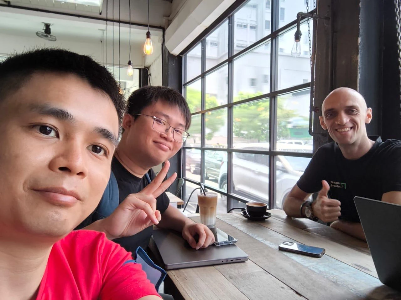 Three people smiling together at a cafe table