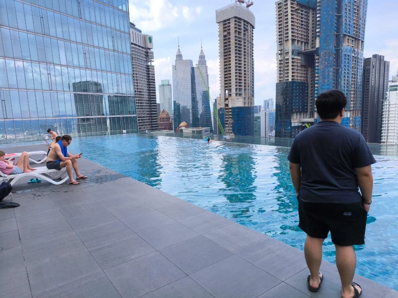 People by a rooftop infinity pool with a city skyline behind