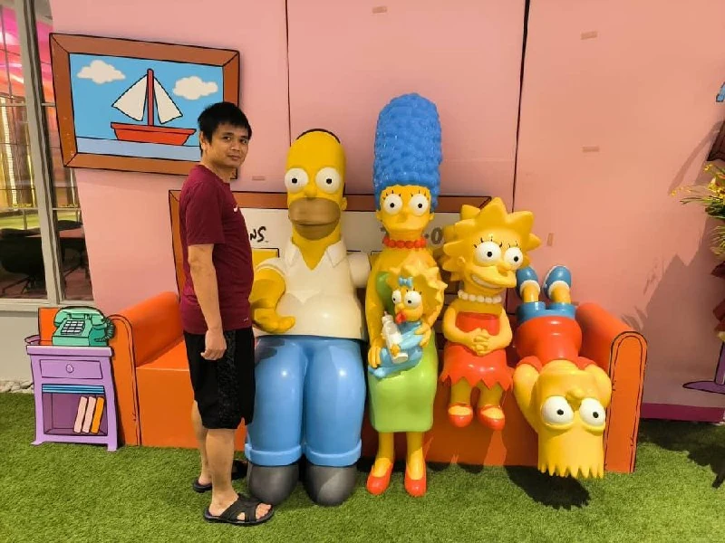 Person posing beside life-size Simpsons character figures