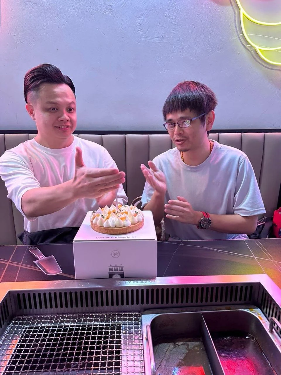 Two people at a restaurant table with a birthday cake