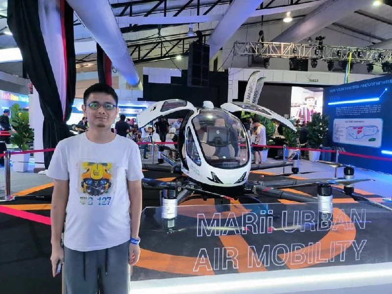 Person standing beside a MARIi Urban Air Mobility display aircraft