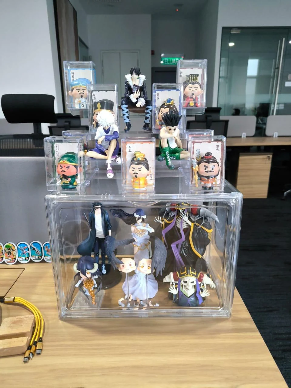 Stacked anime and stylized collectible figures displayed in an office