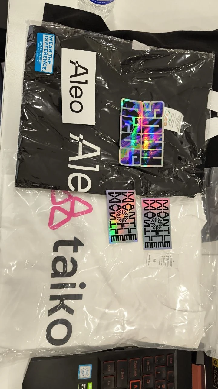 Aleo and Mantle branded event shirts and stickers laid out after the conference
