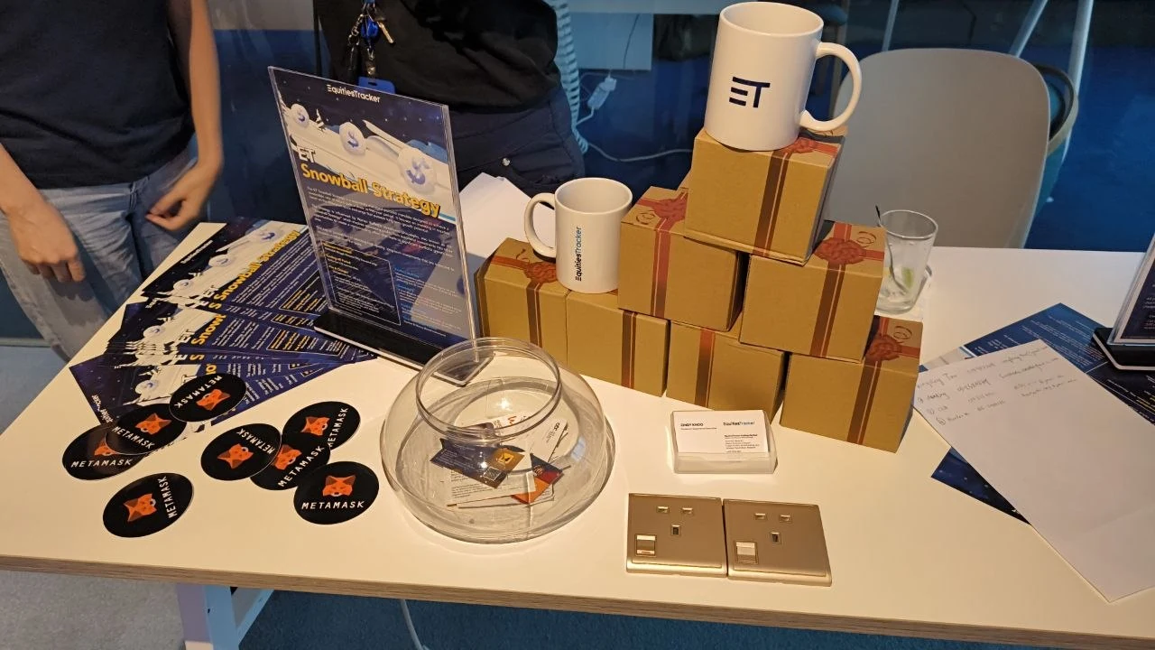 Event booth table with MetaMask stickers, ET mugs, and Web3 handouts
